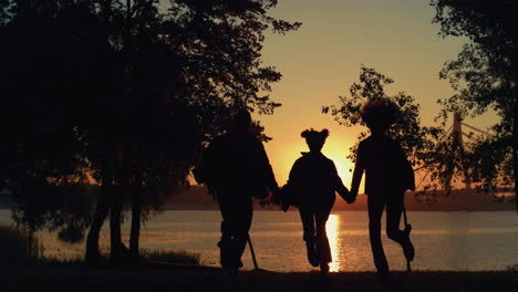 Silueta-Hija-Pareja-Corriendo-En-La-Vista-Del-Atardecer-Del-Río.-Personas-Solidarias-Juntas.