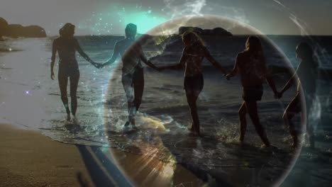 animación de una red global brillante sobre amigas en bikinis tomadas de la mano caminando por la playa