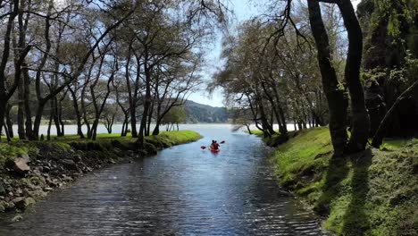 aerial follow couple kayaking river stream surrounded by lush forest, furnas lagoon