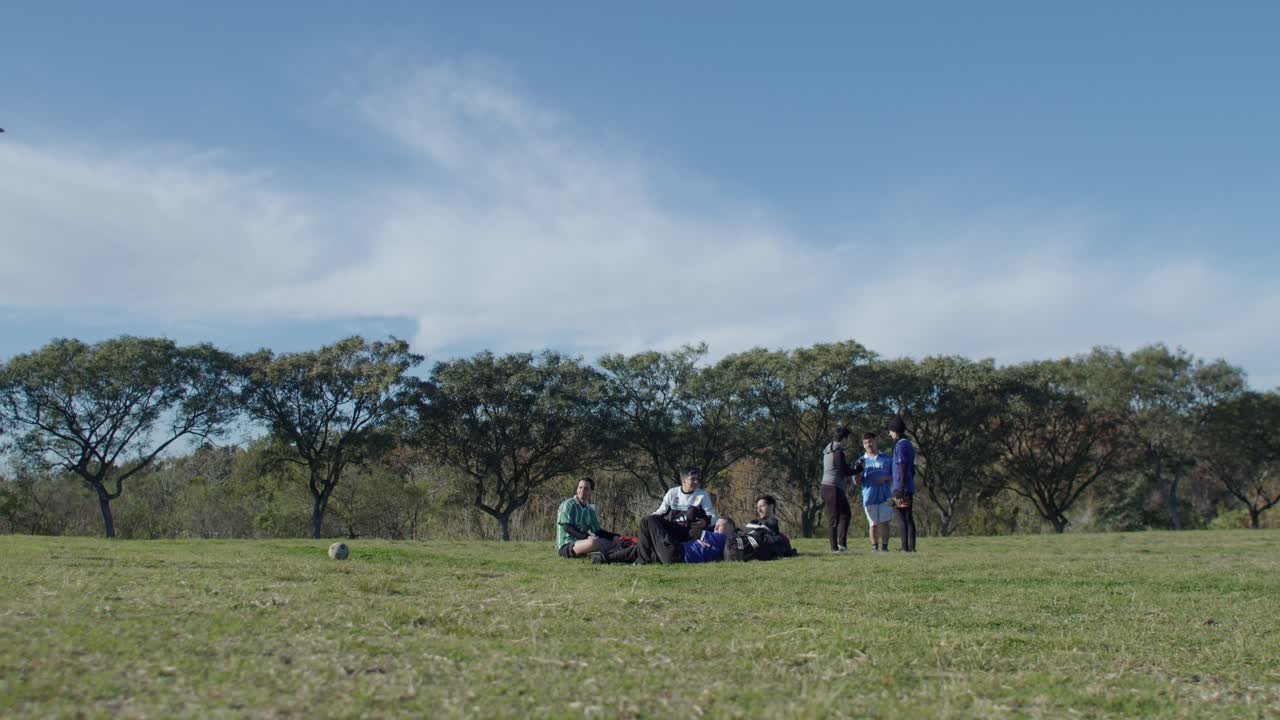 Group of friends enjoying a soccer match on a sunny day in a large green park