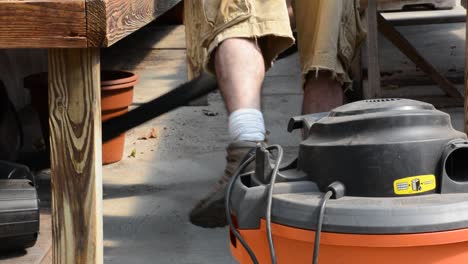 Vacuuming-underneath-wooden-table-around-empty-garden-pot