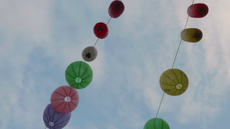 Chinese-lamps-shot-against-the-blue-sky-and-dangling-in-the-wind-between-houses-in-Chinatown,-London