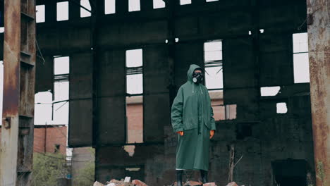 ecologist in safety suit on ruined building background. person in gas mask and protective clothes stands in dangerous place after chemical attack.