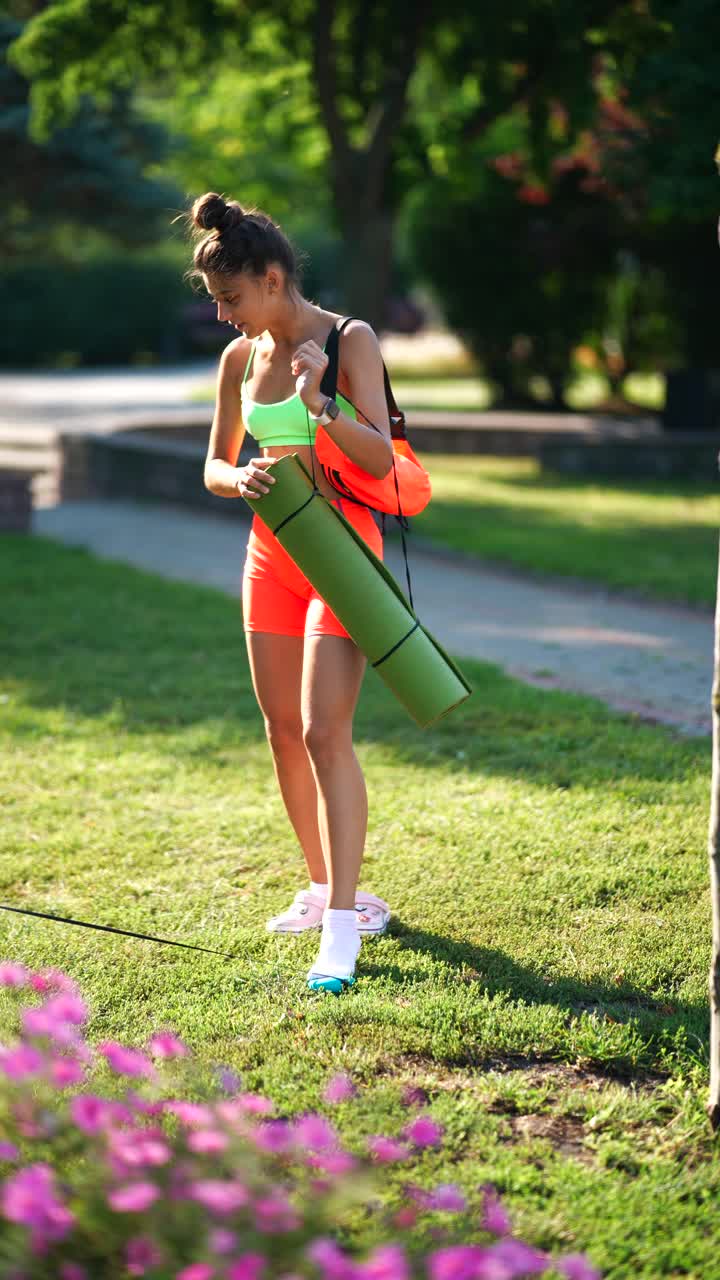 mujer haciendo ejercicio al aire libre con una alfombra de yoga y un perro