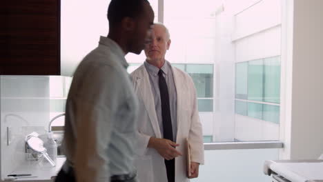 doctor meets with male patient in exam room shot on r3d