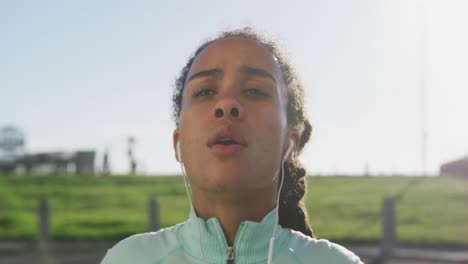 African-american-woman-in-sportswear-wearing-earphones-on-a-sunny-day