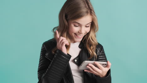 teenage caucasian girl in leather jacket watching videos on her smartphone.