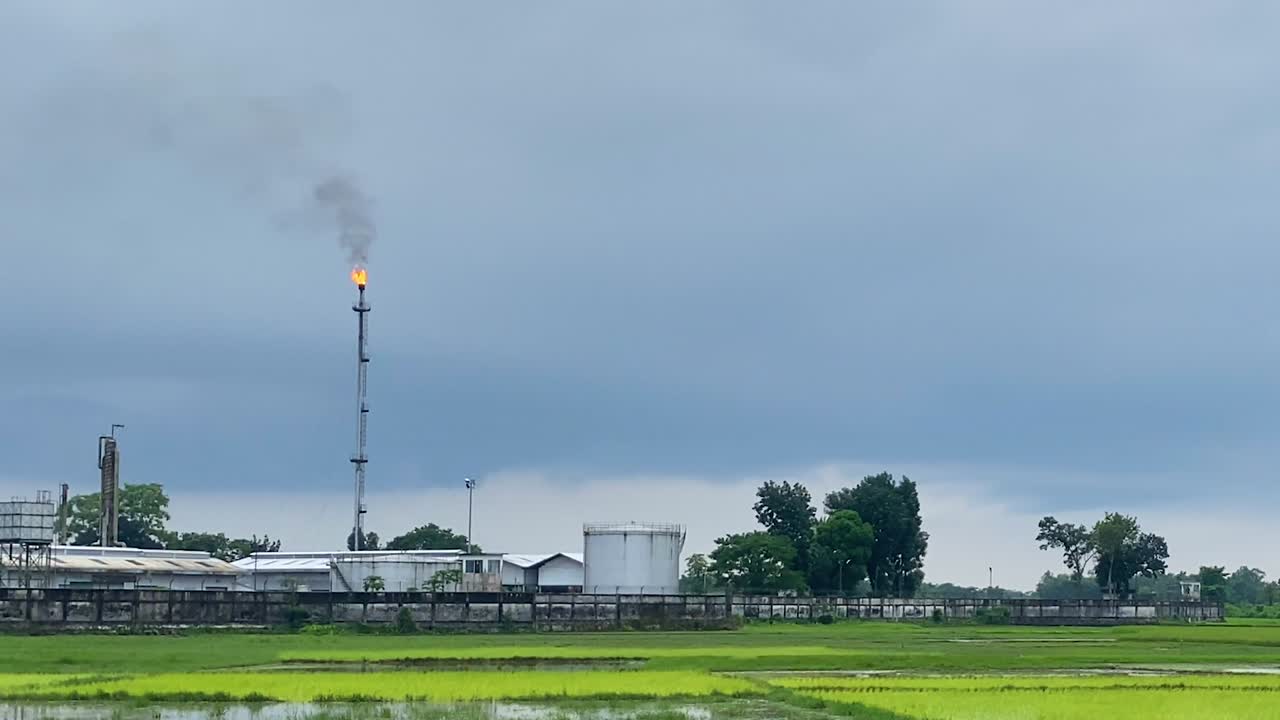 침수된 들판을 둘러싼 가스 공장에서 굴뚝이 불과 연기를 내뿜고 있다