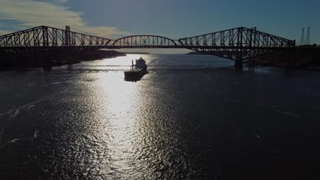 drone shot of a cargo ship traveling under quebec bridge