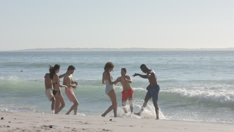 a diverse group of young adults enjoys a day at the beach, running along the shore