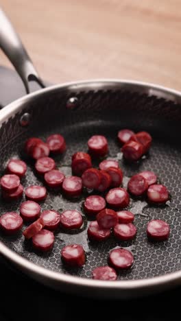 cocinar salchichas en rodajas con cebollas en una sartén