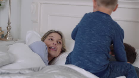 niños felices saltando en la cama despertando madre y padre disfrutando de una mañana lúdica con los niños en la mañana del fin de semana en casa imágenes de 4k