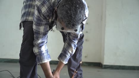 a young south asian man working with an angle grinder to cut slotted angel at his work space