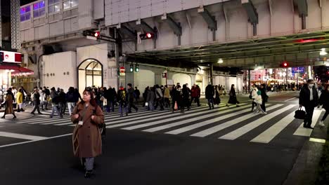 pedestrians crossing busy urban street after dark