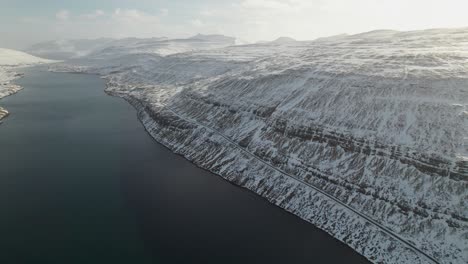 4k aerial drone panorama shot of the majestic fjords and mountains covered in snow of the faroe islands on a sunny and frozen winter day close to the biggest waterfall on the faroe islands foss?