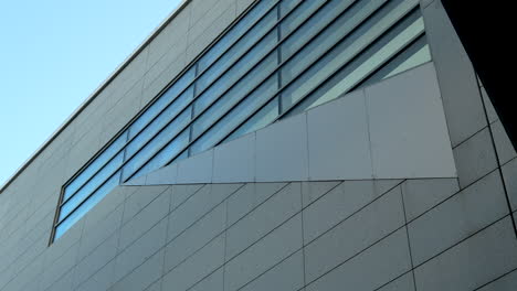 architectural detail of a modern building showing contrasting elements of glass and stone under direct sunlight