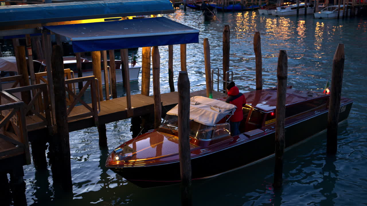 Man standing on a docked boat on the Grand Canal in the evening in Venice, Italy