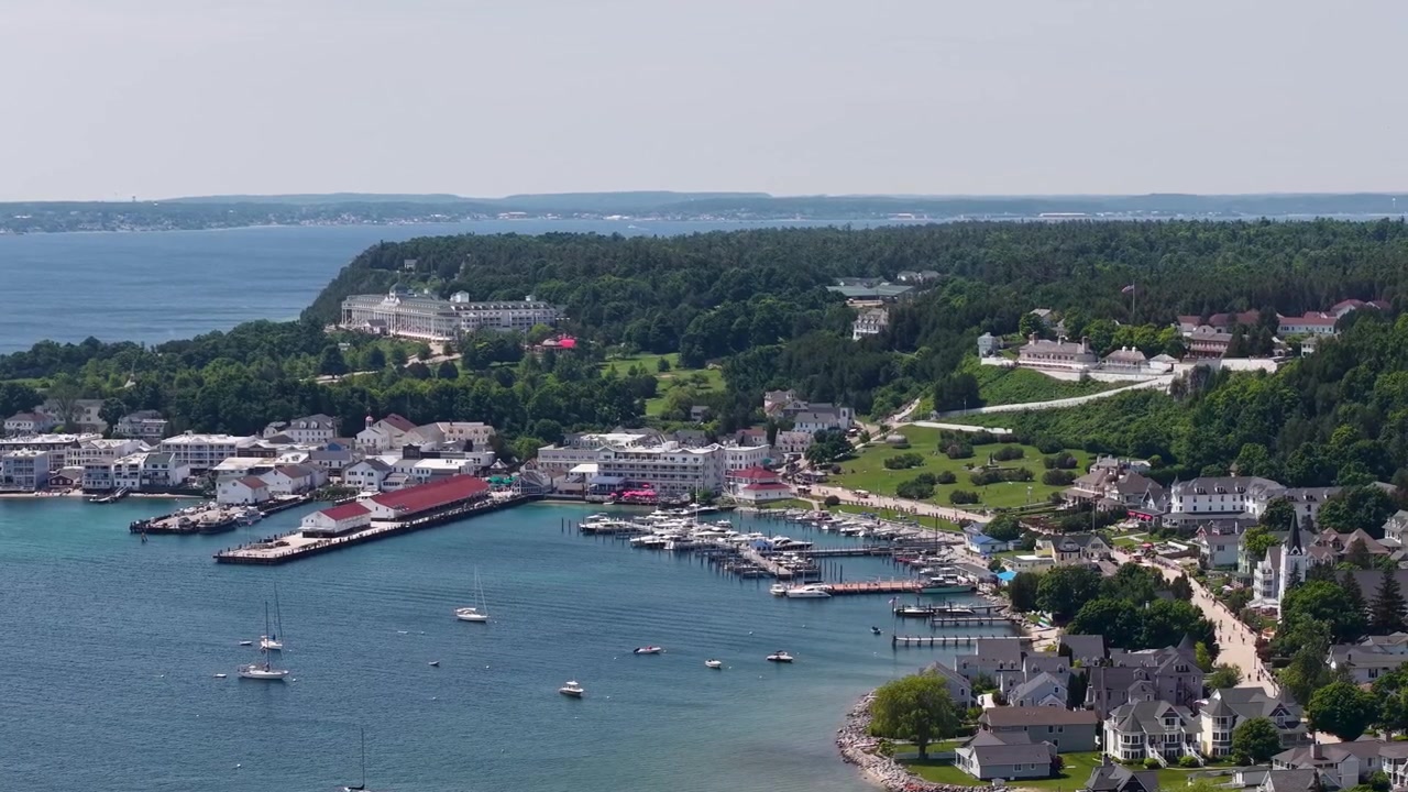 Veduta aerea dall'alto del trafficato porto di Mackinac Island con traghetti, barche a vela, moli ed edifici sul lungomare nel Michigan.
