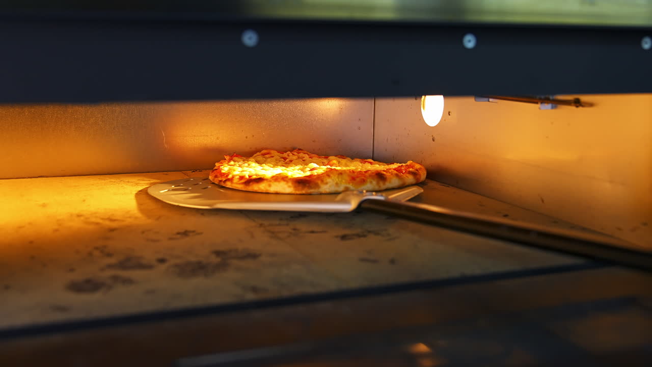 Pizza in oven. Baking pizza. The chef is turning hot pizza with a spatula in a stove. Process of cooking pizza in pizzeria. Tasty cookery.