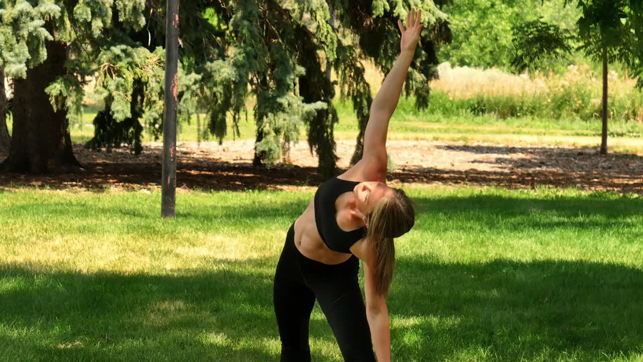 Lean strong woman exercises in a park with graceful yoga poses. Drone 4k. Beautiful scene reminds us of being agile and flexible