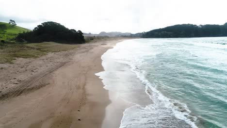 Playa-De-Agua-Caliente-Con-Reflejos-De-Luz-Solar-En-La-Orilla-Y-Selva-Tropical-En-El-Fondo---Inclinación-Aérea-Del-Carro