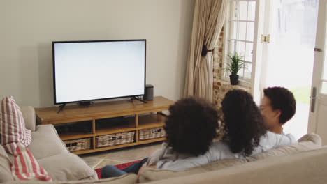 Una-Pareja-De-Lesbianas-De-Raza-Mixta-Y-Su-Hija-Viendo-La-Televisión-Sentada-En-El-Sofá