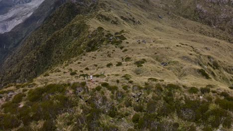 Breathtaking-aerial-of-female-photographer-taking-photos-of-Fox-Glacier-from-mountain-summit