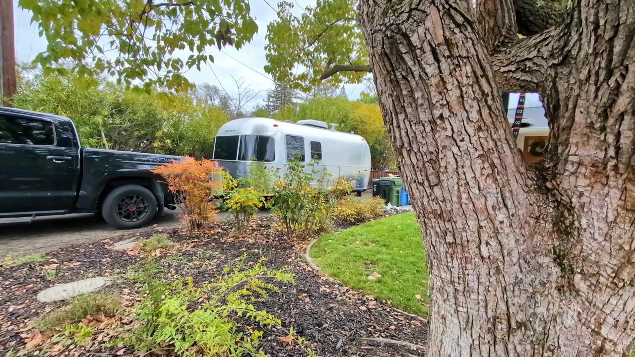 Una vista di un camper Airstream e un pick-up parcheggiati nel cortile del giardino. Carrellata.