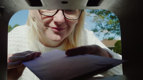 woman collects post from mail box