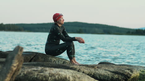 female triathlete resting on lakeshore after swimming