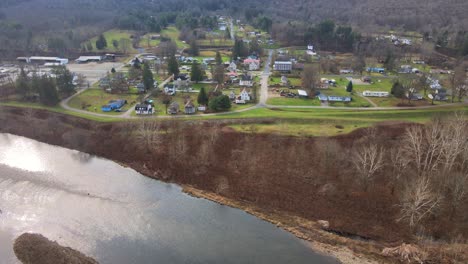 Drone-video-panning-sideways-above-a-small-town-in-America,-on-the-banks-of-a-river,-as-well-as-a-highway-and-bridges