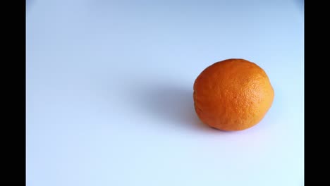 whole orange fruit doing circles in stop motion isolated on white background