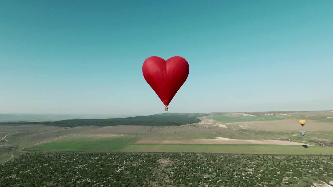 Balon na ogrzane powietrze w kształcie serca nad malowniczym krajobrazem