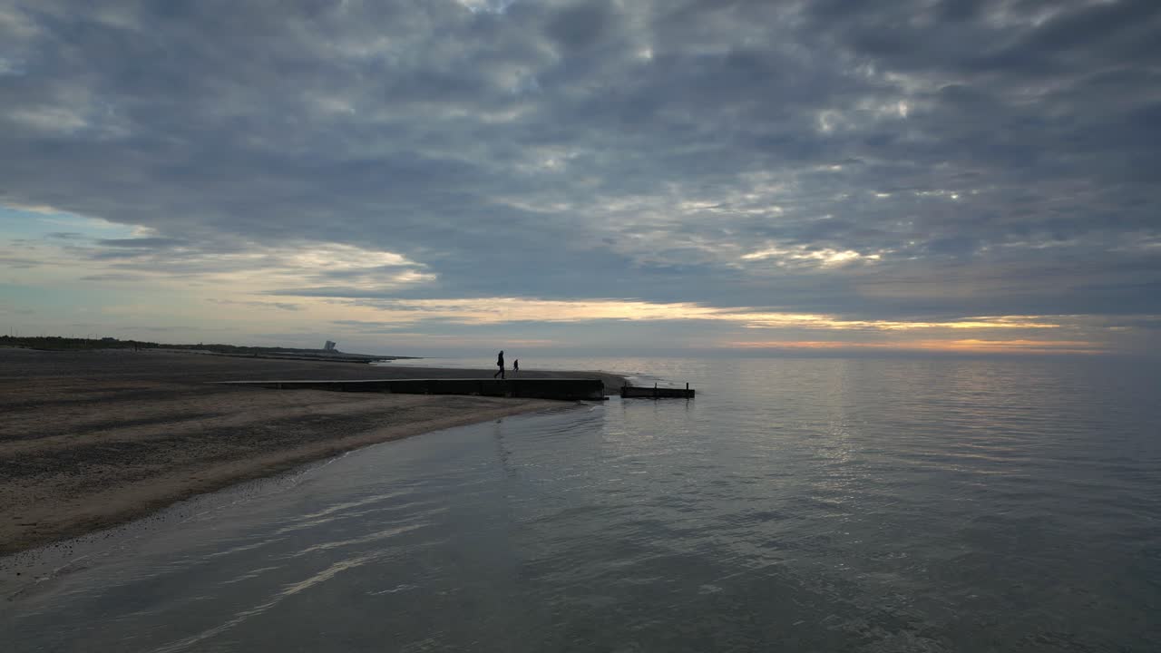영국 랭커셔 플리트우드 해변에서 황혼에 부두의 끝을 향해  ⁇ 고 있는 남자의 실루 ⁇ 의 느린 움직임 넓은  ⁇