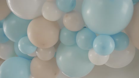soft pastel balloons in blue white and beige clustered on ceiling for festive baby event