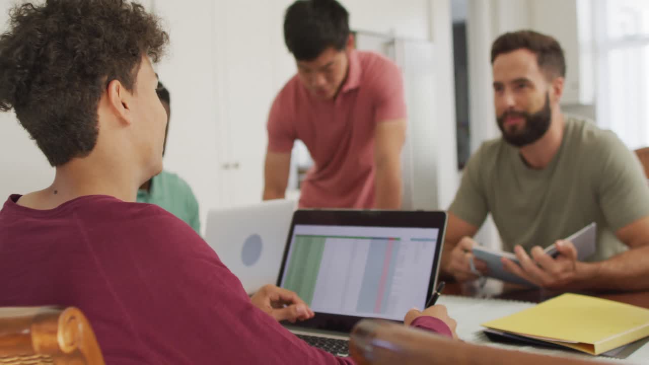 diversos amigos hombres felices hablando y usando computadora portátil en la sala de estar