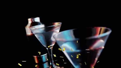 Golden-confetti-falling-over-olives-falling-into-cocktail-glasses-against-grey-background