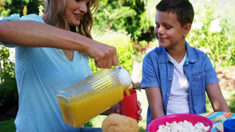 Mother-pouring-juice-in-glass-while-having-meal