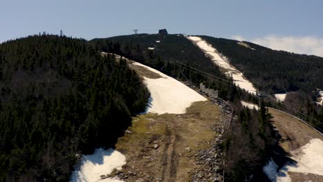 ski mountain after season close during spring with melting snow and historic tram building drone aerial 4k 30p