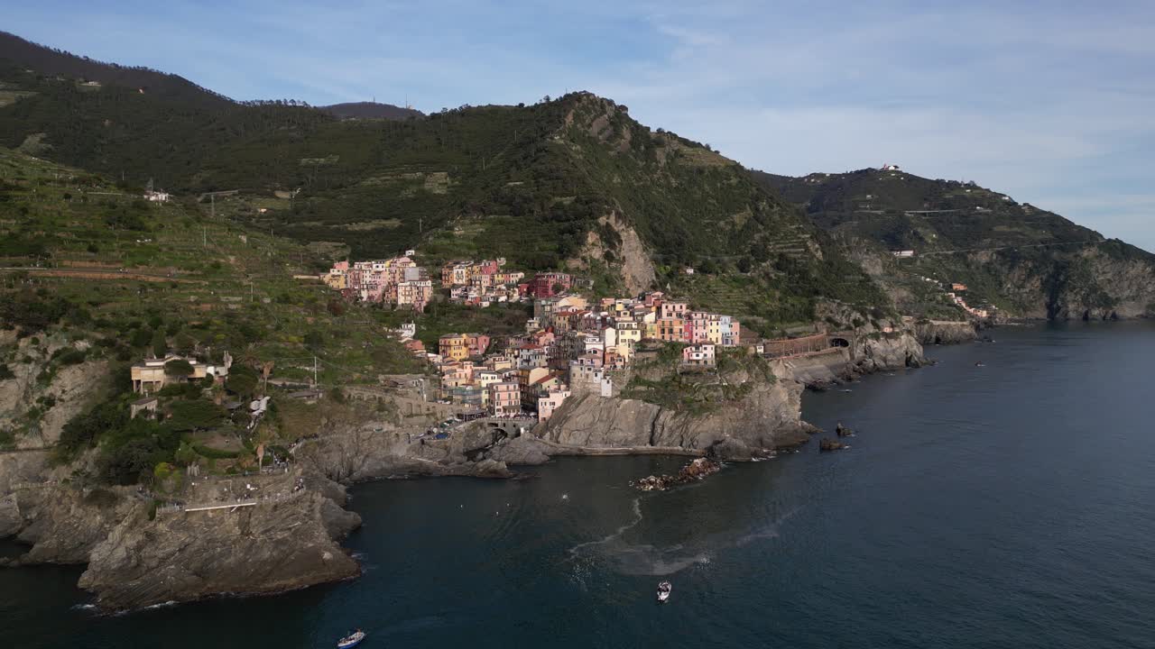 Manarola Cinque Terre Italia, avvicinamento aereo cinematografico mentre il paese è illuminato dal sole in una giornata nuvolosa