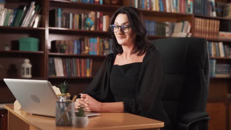 The-woman-is-sitting-behind-her-laptop,-surrounded-by-many-books