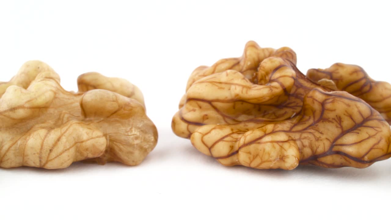 Row of walnuts without the shell are moving horizontally from one side of the frame to other. Isolated on the white background. Close-up. Macro.