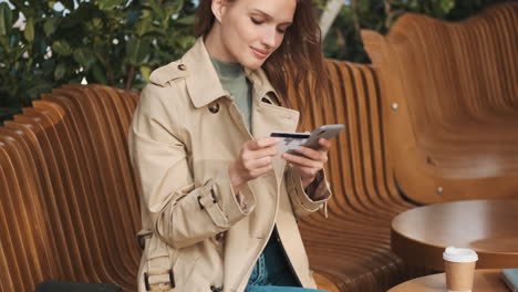 estudiante caucásica haciendo compras en línea en el teléfono inteligente al aire libre.