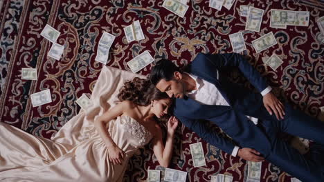 couple lying on a carpet covered in money