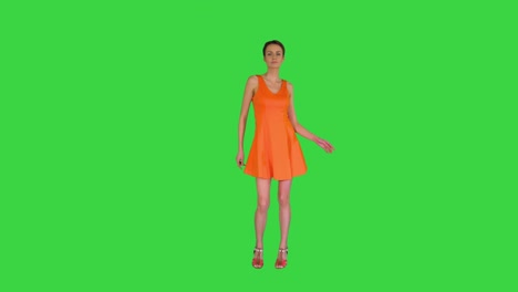 una mujer bonita con el cabello corto bailando en vestido de sol naranja en una pantalla verde, clave de croma