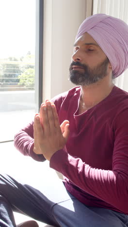 vertical video: meditating at home, man with turban practicing mindfulness in living room