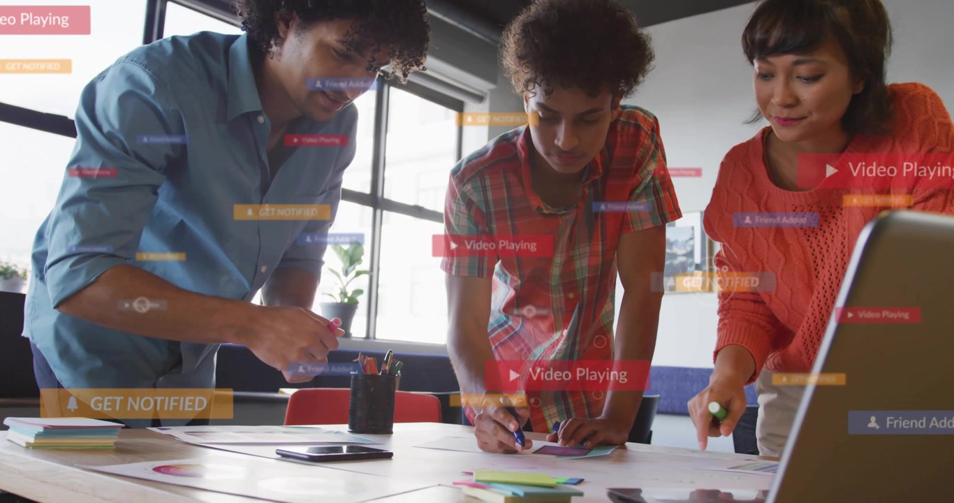 3-person team leaning over charts tapping cell moving notes sparking badges crossing table business