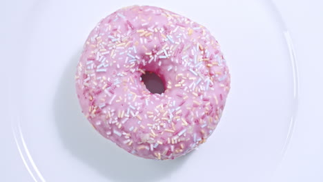 wide shot of a pink doughnut spinning on a white plate