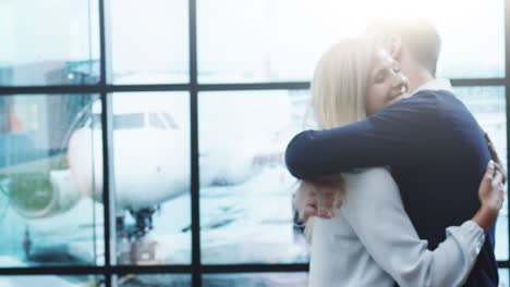 hombre y mujer se encuentran en la sala de llegada del aeropuerto. la gente se abraza y sonríe.
