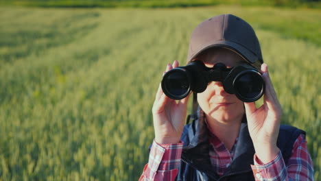 A-Woman-Looks-Through-Binoculars-Standing-In-The-Endless-Green-Field